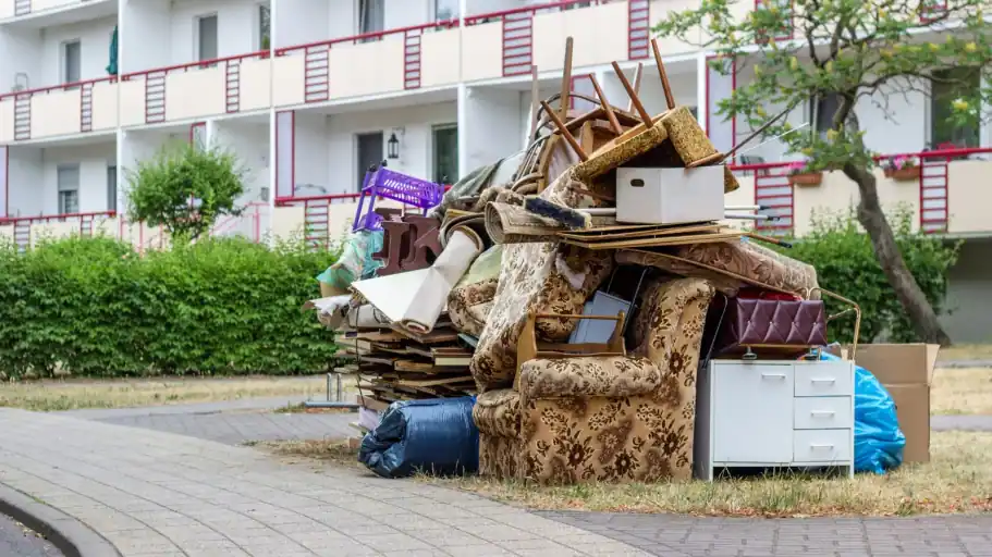 Sperrmüll aus Möbeln, Teppichen und Säcken vor einem Wohnhaus