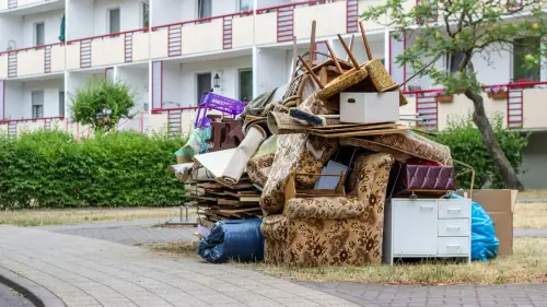 Sperrmüll aus Möbeln, Teppichen und Säcken vor einem Wohnhaus